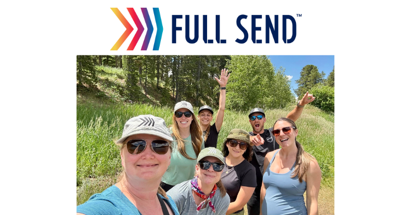 Group of six people outdoors on a sunny day, smiling and posing for a selfie during a hike. They are wearing casual clothing, sunglasses, and hats with the “Full Send” logo, with trees and grassy hills in the background. The “Full Send” logo, featuring multicolored arrows and bold navy text, is displayed above the photo.