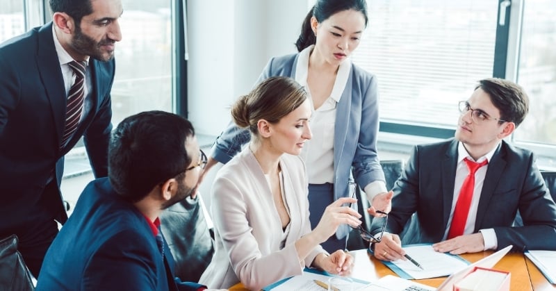 Accounting professionals collaborating around a conference table while reviewing documents and discussing business processes.