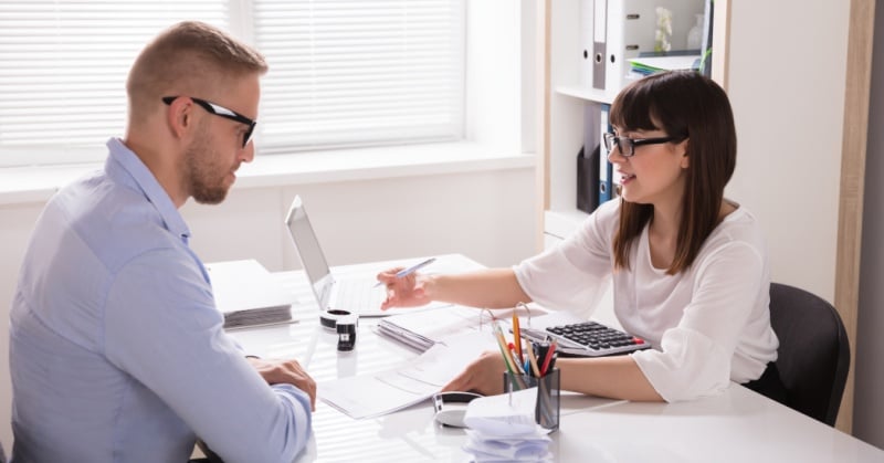 Financial advisor meeting with a small business client to review tax documents and planning strategies at a modern office desk.