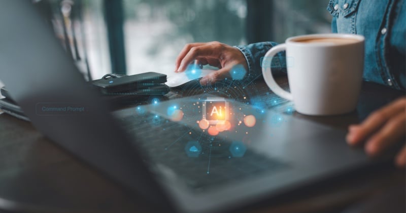 Person working on a laptop with a coffee mug beside them, overlaid with a digital AI interface symbolizing artificial intelligence and data integration.
