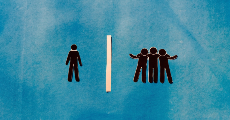 One silhouette stands alone on the left, while three stand with arms around one another on the right, separated by a white vertical divider on a blue background.