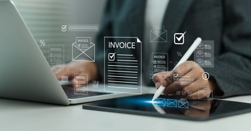 A professional working on a tablet and laptop reviews digital invoices, with virtual invoice icons and payment symbols overlaying the screen, representing modern, integrated billing and payment processes.