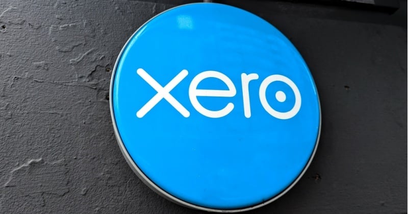 Xero company logo on a blue circular sign mounted against a dark wall.