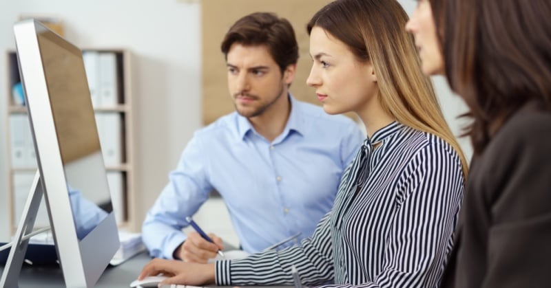 Accounting professionals reviewing information together at a desktop computer in an office