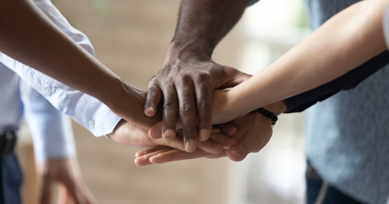Close-up of a diverse group of people stacking their hands together in a gesture of teamwork and unity.