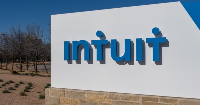 Intuit logo displayed in blue lettering on a white outdoor sign with landscaping and trees in the background.