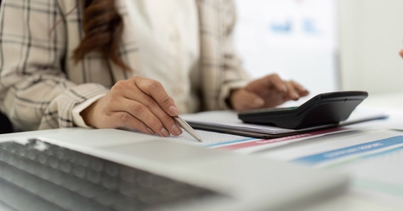 Accountant reviewing financial reports with a calculator during accounting and finance planning