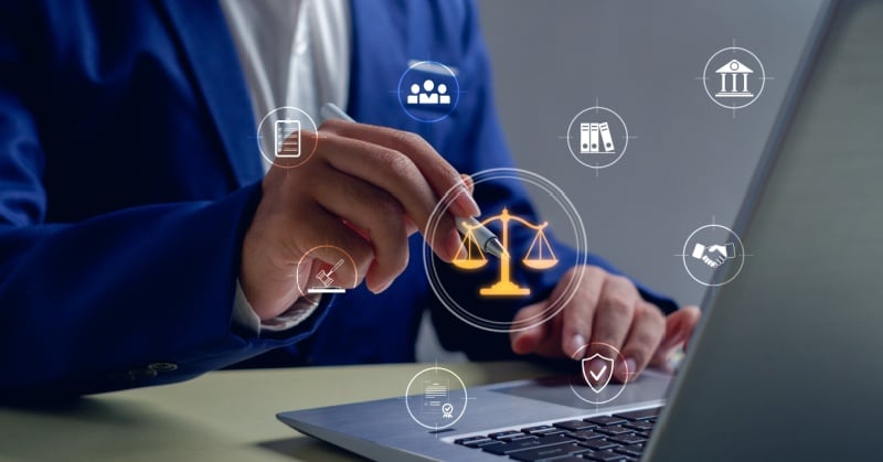 Attorney using a laptop while selecting a digital legal scales icon surrounded by law, compliance, and client service symbols.