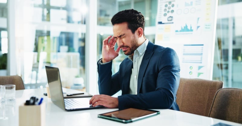 Business professional reviewing information on a laptop while appearing concerned about complex data.