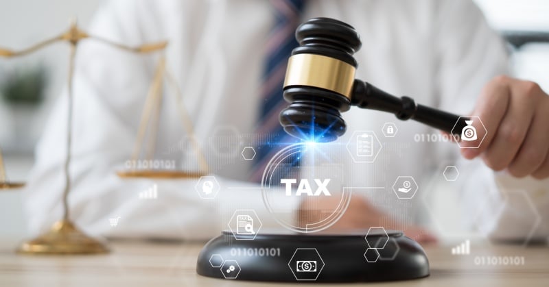 Tax law concept with a judge’s gavel, scales of justice, and digital tax icons overlaid in the foreground.