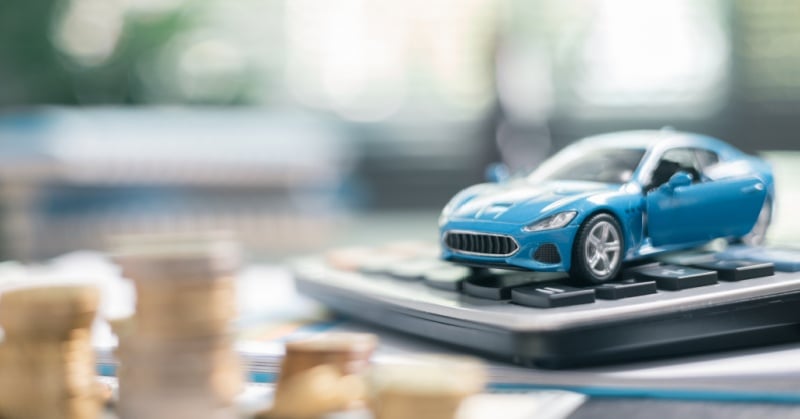 Toy sports car on a calculator surrounded by coins, representing accounting practice performance and financial strategy