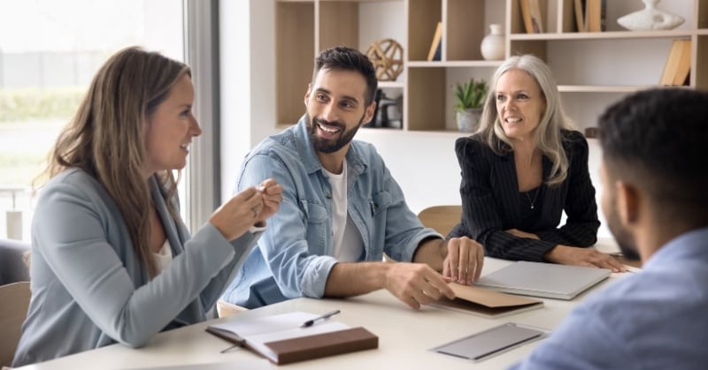Four professionals having an engaged discussion around a conference table in a modern office.
