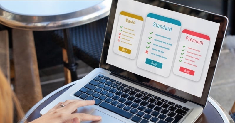 A person using a laptop with a screen displaying three subscription pricing plans labeled Basic, Standard, and Premium, each showing a checklist of features and a "Buy" button.        Ask ChatGPT