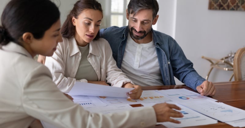 Financial advisor reviewing charts and reports with a couple during a client meeting.