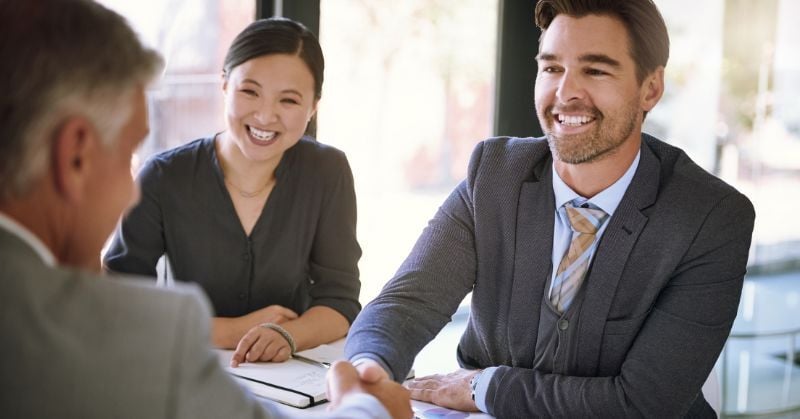 Three accounting professionals smiling during a client meeting, illustrating relationship-building and strategic client onboarding.