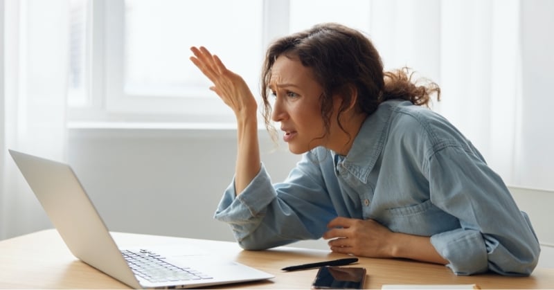 Frustrated accounting professional struggling with AI tools and technology overload while working on a laptop.