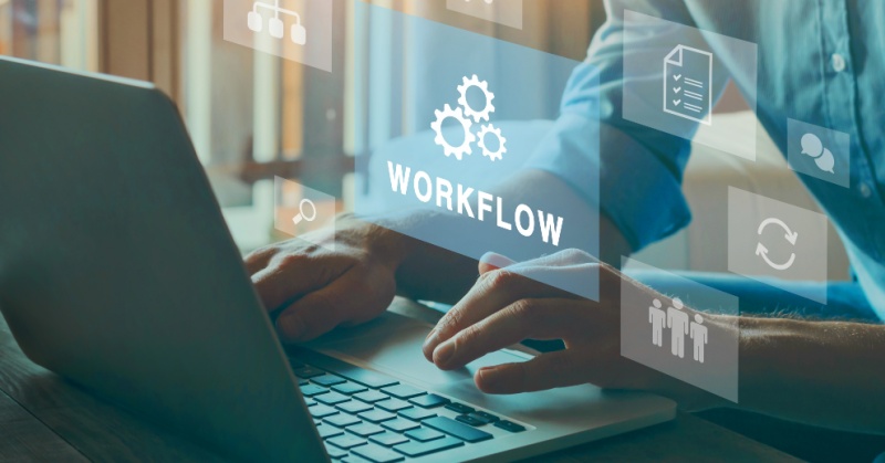 Person working on a laptop with virtual icons and the word 'WORKFLOW' displayed, representing digital process management and automation.