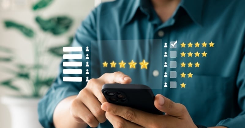 A person in a teal shirt uses a smartphone while interacting with a digital five-star rating interface.