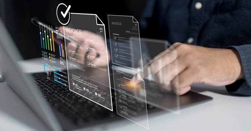 A person interacting with a laptop displaying digital invoices and data dashboards via augmented reality or virtual interface, symbolizing automation and digital transformation in accounting and finance.