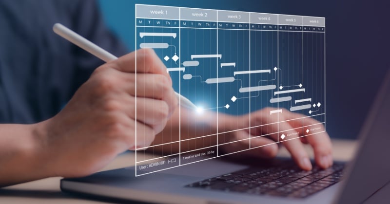 A person uses a stylus on a laptop to interact with a digital Gantt chart displaying a multi-week project timeline.