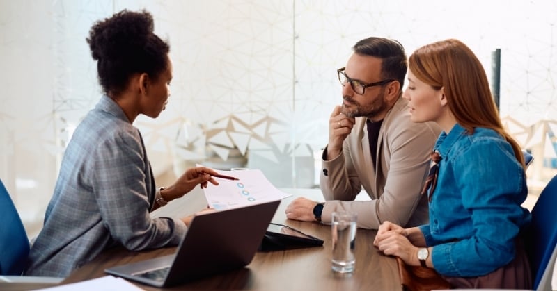 Accounting advisor reviewing a financial report with two clients during a business consultation.
