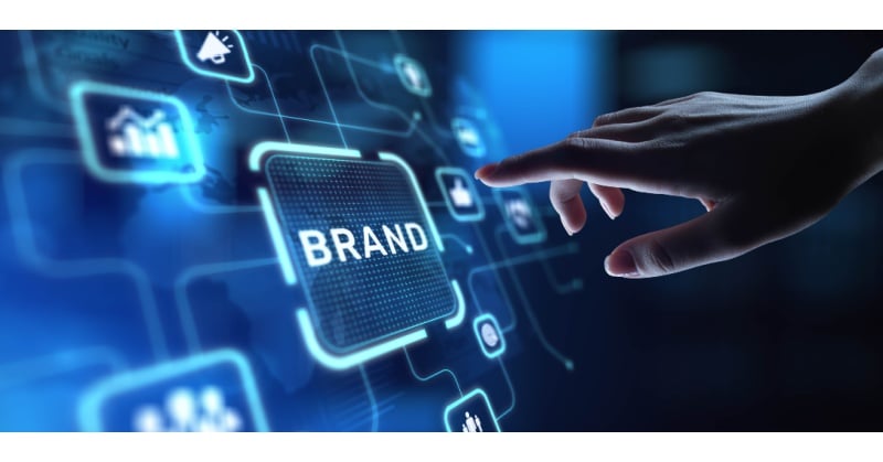 A hand reaches toward a glowing digital interface with the word “BRAND” highlighted at the center. Surrounding icons represent marketing, analytics, and digital strategy, symbolizing the importance of branding in a technology-driven business environment.