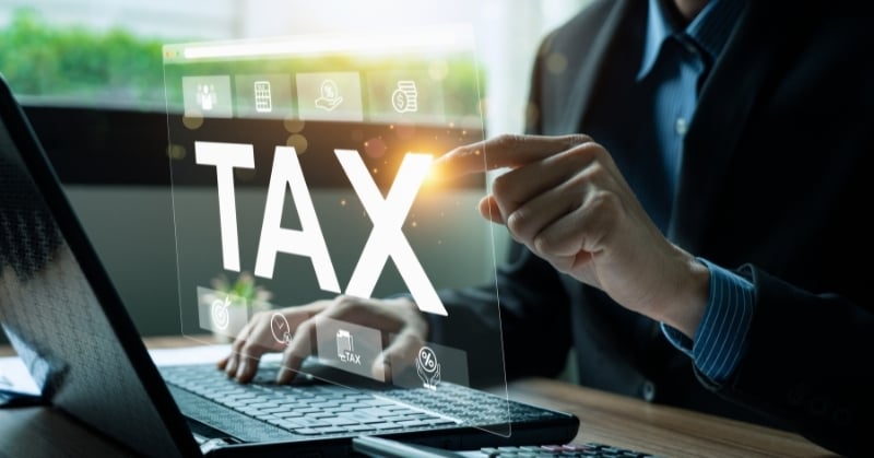 Business professional using a laptop and interacting with a digital tax interface.