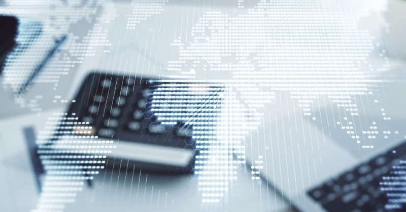 Abstract digital world map overlaying an office desk with a calculator, documents, and laptop, symbolizing global finance and outsourcing.