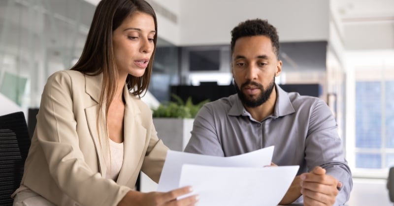 Two professionals reviewing documents together during a business advisory meeting in a modern office.