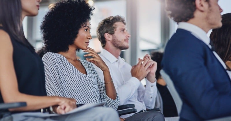 Professionals attentively listen during a seminar, emphasizing continual learning and growth in a collaborative environment.