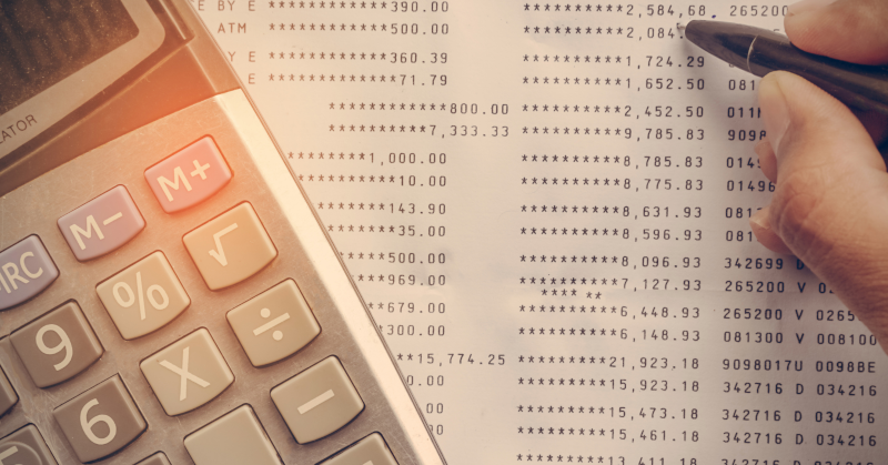 paper accounting sheet with amounts printed calculator and human hand with pen partially visible