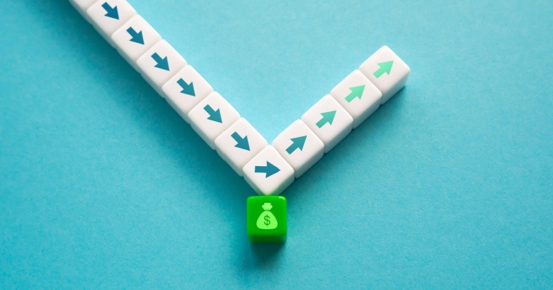 blue background green cube with bag of money icon dollar symbol on it deflecting eleven white cubes with blue and green arrows pointing down then up