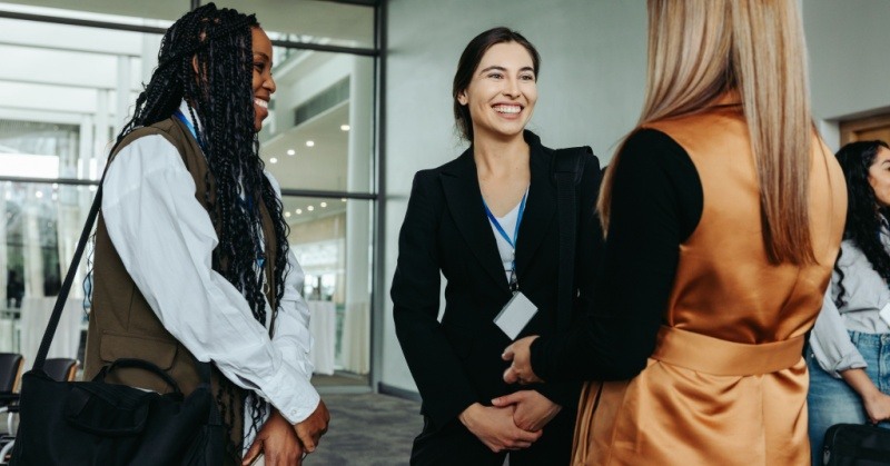 networking event three women standing in circle with business casual attire nametags smiling